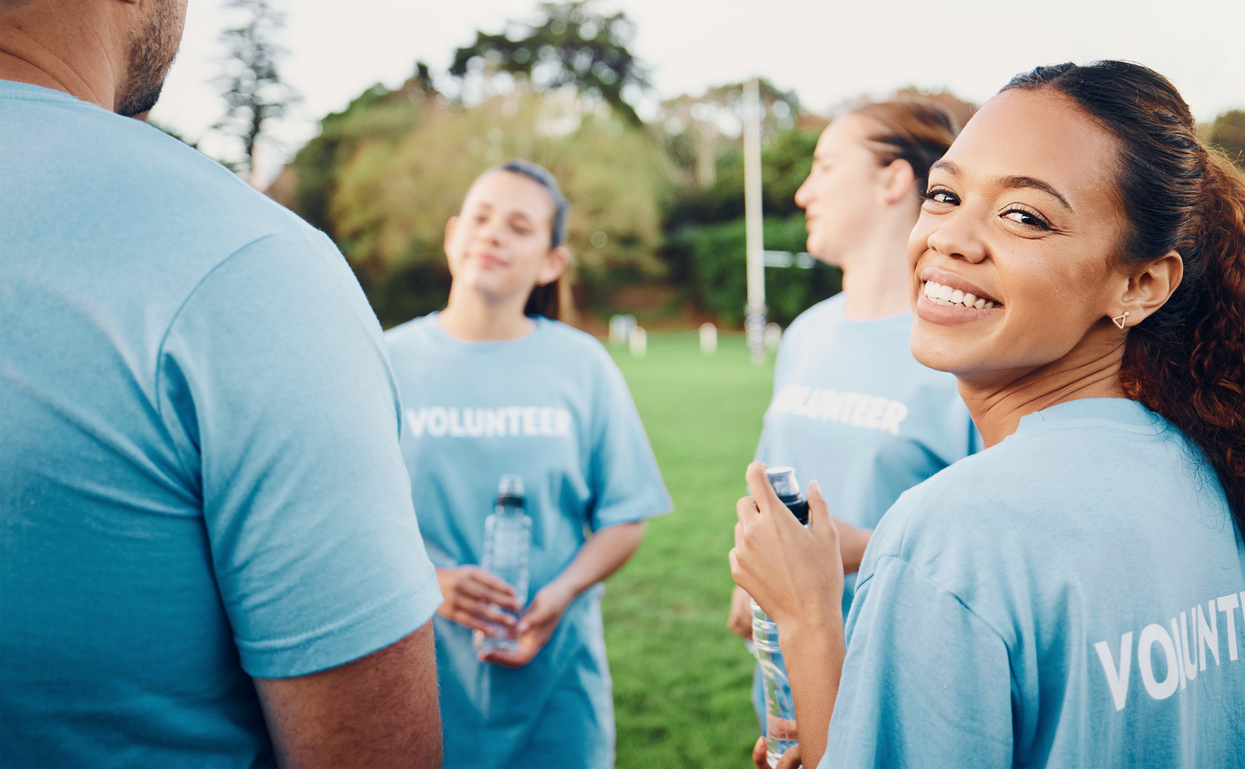 Smiling volunteer woman with team outdoors for climate change, charity cleaning and recycling.