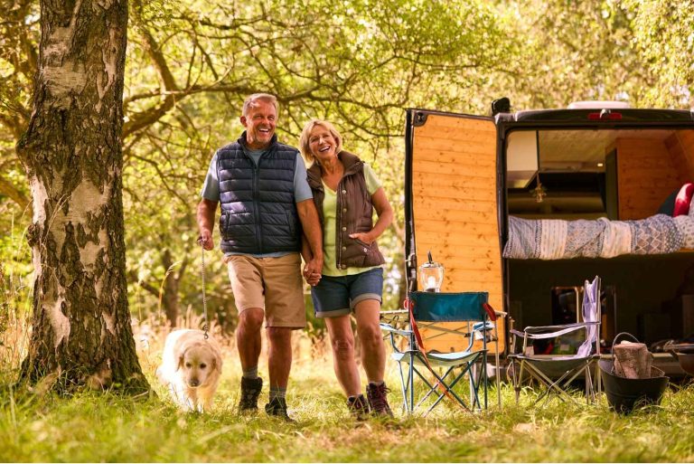 Senior Couple Camping in Countryside with RV Taking Labrador Dog for a Walk
