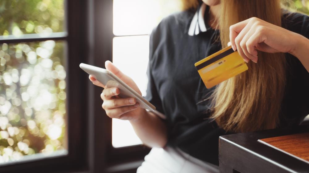 Close up of female hands holding a smart phone and a credit card for online shopping.