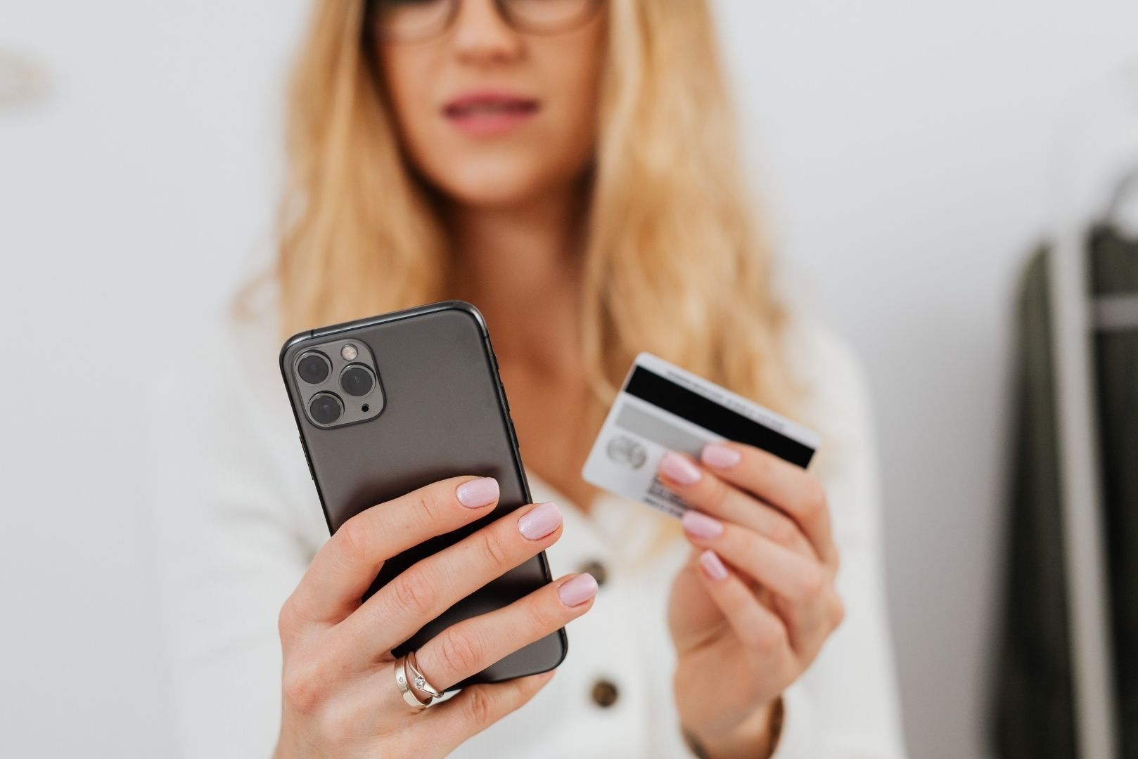 A woman holding a smartphone and a credit card, appearing to make an online purchase.