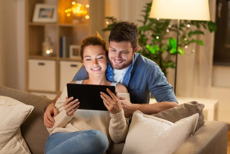 couple sitting on couch using tablet